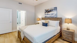 A bedroom with a wooden bed, two bedside tables with lamps, a ceiling fan, and a painting on the wall. - Beautiful dog-friendly condo with pool, central AC, & washer/dryer (Tucson)