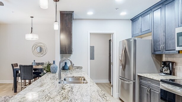 A modern kitchen with a marble island, stainless steel appliances, and pendant lighting. - Beautiful dog-friendly condo with pool, central AC, & washer/dryer (Tucson)