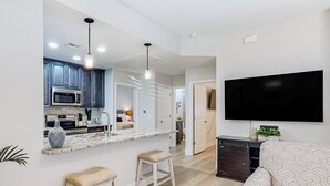 A modern kitchen with a marble countertop, bar stools, and a built-in microwave. - Beautiful dog-friendly condo with pool, central AC, & washer/dryer (Tucson)