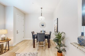 A dining area with a table, chairs, a hanging light fixture, a door, and a wall-mounted mirror. - Beautiful dog-friendly condo with pool, central AC, & washer/dryer (Tucson)