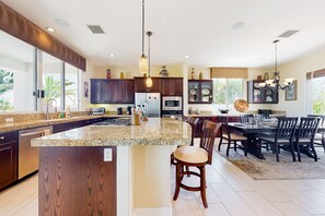 A modern kitchen with granite countertops, dark wood cabinets, and stainless steel appliances.