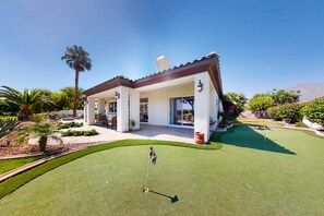 A modern house with a patio, a flag, and a well-maintained lawn.