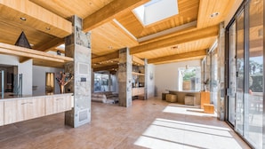 Un intérieur spacieux avec de hauts plafonds, des poutres en bois et de grandes fenêtres qui laissent entrer la lumière naturelle.