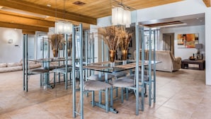 Un espace repas moderne avec une table en verre, des chaises en métal et un plafond en bois.