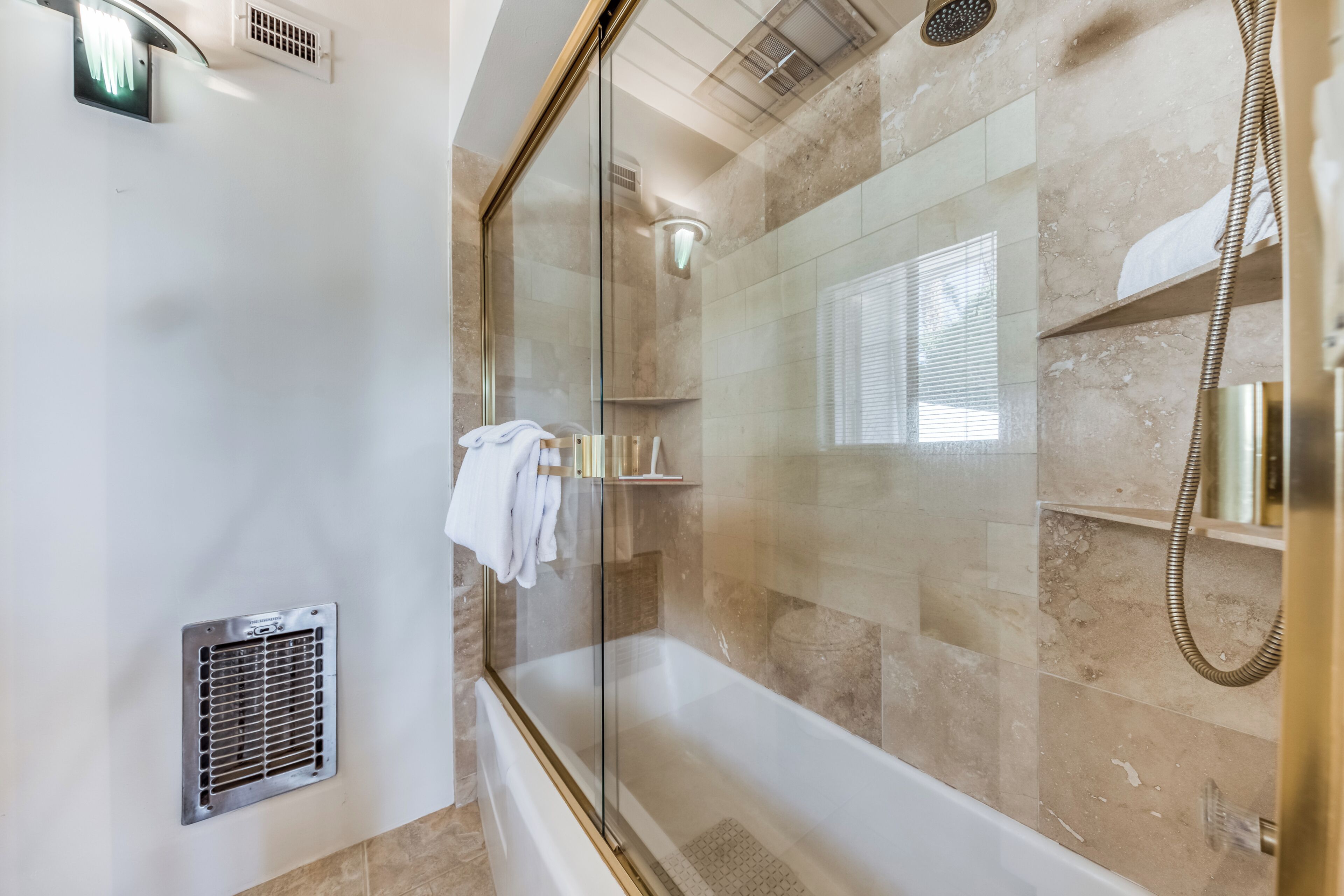 Un bany modern amb dutxa envidriada, banyera i un lavabo amb prestatges.
