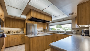 Une cuisine moderne avec des armoires en bois, un réfrigérateur en acier inoxydable et un grand îlot central.