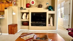 Ein Wohnzimmer mit Kamin, Fernseher und verschiedenen Dekorationselementen.