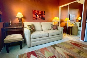 Ein Wohnzimmer mit einer Couch, zwei Lampen, einem Teppich und einem Gemälde an der Wand.