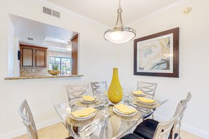 A dining area with a glass table, clear chairs, and a yellow vase centerpiece. - Bright Dog Friendly condo with inviting patio, washer/dryer on a Golf Course (Cathedral City)