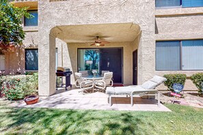An outdoor patio with a table and chairs, a ceiling fan, and a lounge chair. - Bright Dog Friendly condo with inviting patio, washer/dryer on a Golf Course (Cathedral City)