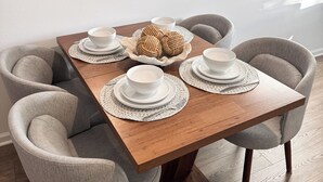A dining table with four chairs, a mirror, and a kitchen in the background. - Modern Coastal Townhouse Near Beach & DT - St. Augustine (St. Augustine)