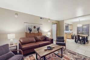 A living room with a brown sofa, a coffee table, and a patterned rug. - Charming Condo w/ Red Rock views, shared pool/hot tub & pickleball/tennis courts (Sedona)