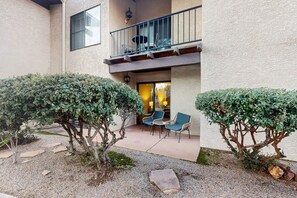 A building with a balcony, outdoor seating, and trimmed bushes. - Charming Condo w/ Red Rock views, shared pool/hot tub & pickleball/tennis courts (Sedona)