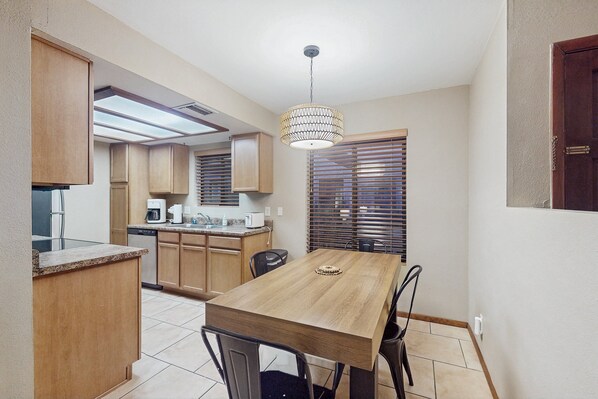 A compact kitchen with a dining table, chairs, and a hanging light fixture. - Charming Condo w/ Red Rock views, shared pool/hot tub & pickleball/tennis courts (Sedona)
