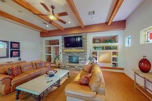 A spacious living room with a stone fireplace, leather sofas, and a ceiling fan. - Sunny townhome with a lovely patio & W/D - pool, game room, and gym access (Oro Valley)