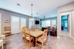 A spacious dining area with a wooden table and chairs, a chandelier, and a stone accent wall. - Beautiful desert home near trailheads with yard, grill, and mtn views - dogs ok (Phoenix)