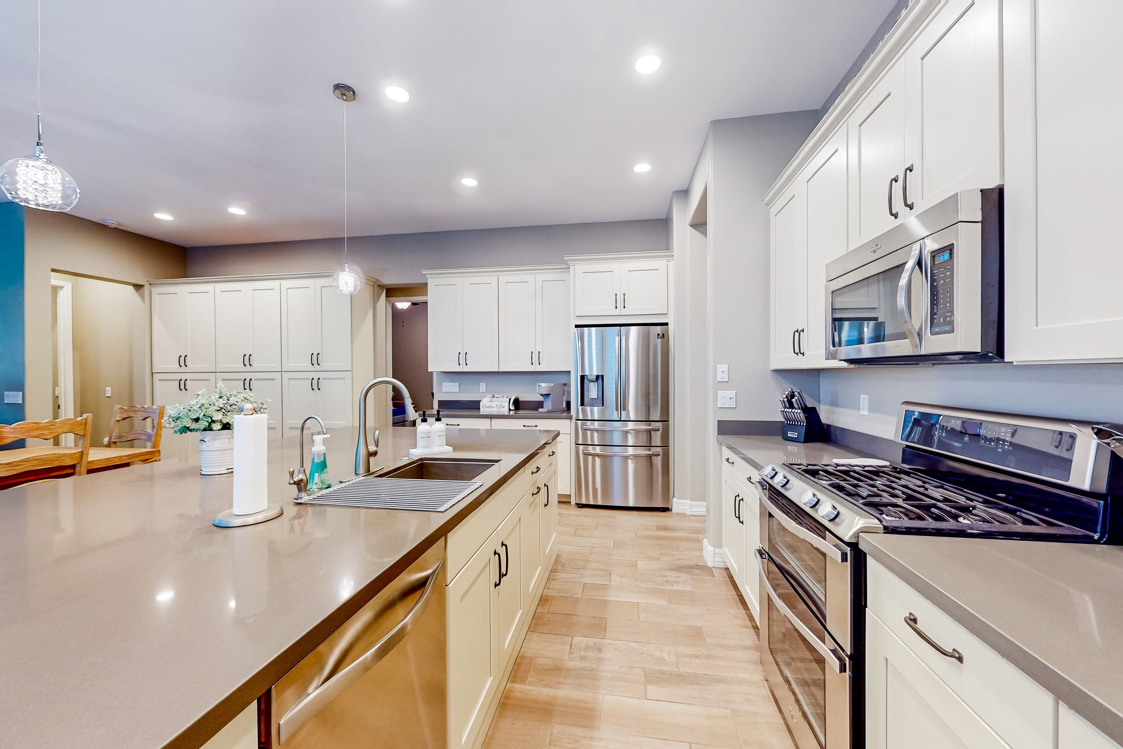 A modern kitchen with stainless steel appliances, a central island, and a view into the dining area.