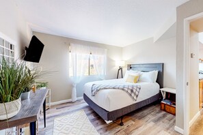 A bedroom with a bed, bedside table, lamp, potted plants, and a window with curtains. - Mountain view stay with fireplace, resort-style amenities, central AC, & W/D (Tucson)