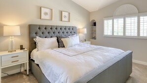 A bedroom with a large bed, two bedside tables, and a window with blinds. - Delightful golf escape with pool, lawn games, pool table, fast WiFi & central AC (Phoenix)