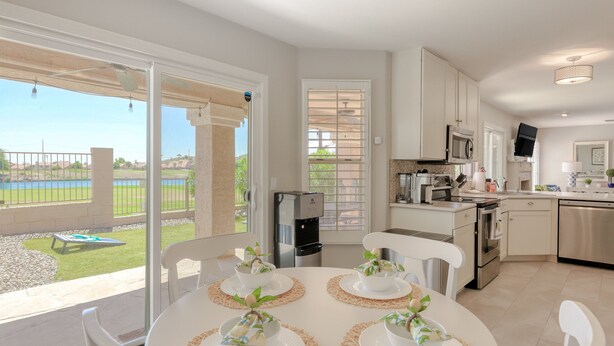 A modern kitchen with white cabinets, stainless steel appliances, and a large window overlooking a patio. - Delightful golf escape with pool, lawn games, pool table, fast WiFi & central AC (Phoenix)