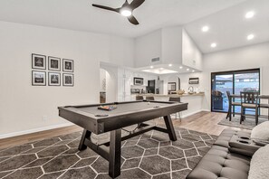 A modern living room with a pool table, a sofa, and a dining area with a view. - Contemporary home with a private pool, hot tub & fast WiFi (Scottsdale)