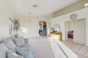 A spacious living area with a sofa, a wooden console table, and a large mirror. - Inviting home with pool, hot tub, enclosed yard, fast WiFi, & W/D (Phoenix)