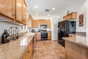 A kitchen with wooden cabinets, a black refrigerator, a microwave, and a stove.
