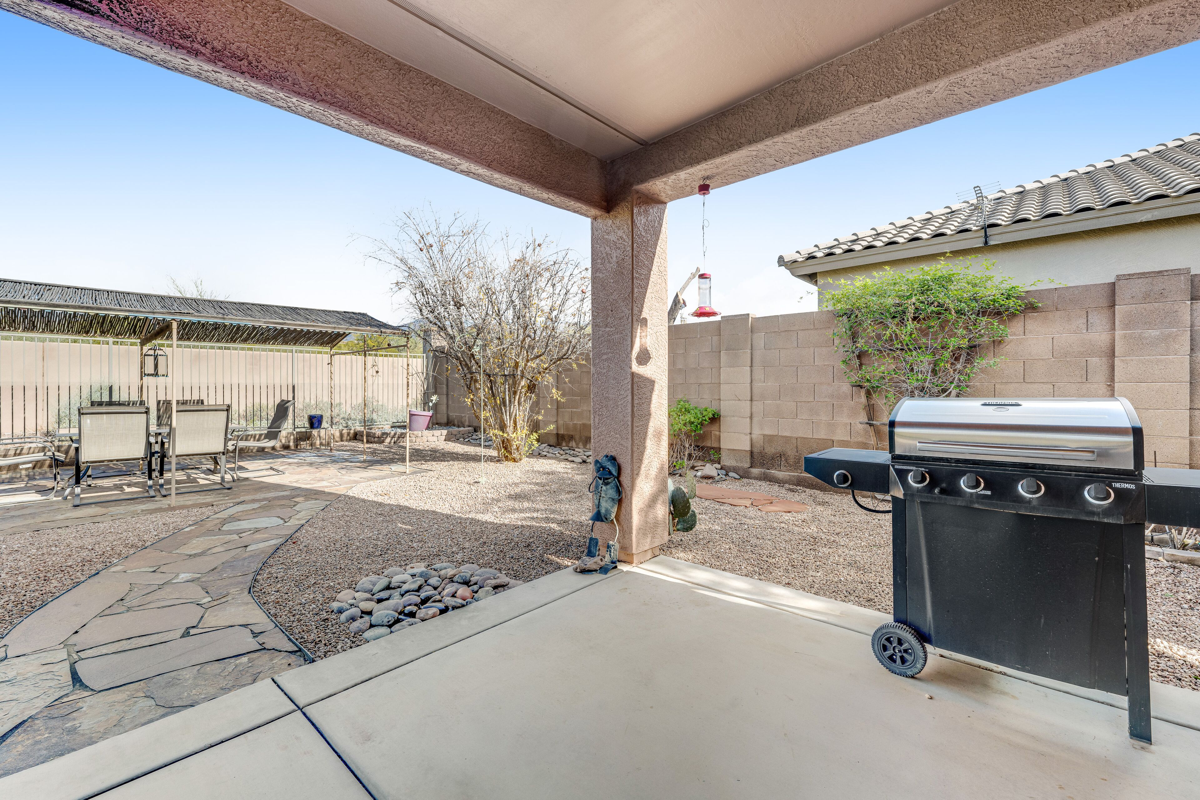 A patio area with a barbecue grill, stone pathway, and outdoor furniture.