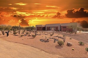 A building with a desert landscape, a gravel driveway, and sparse vegetation. - 3-suite home on 2.5 acres, complete with a private pool & large furnished patio (Scottsdale)
