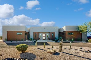 A modern two-story house with a flat roof, a central entrance, and a small front garden with cacti and shrubs. - 3-suite home on 2.5 acres, complete with a private pool & large furnished patio (Scottsdale)
