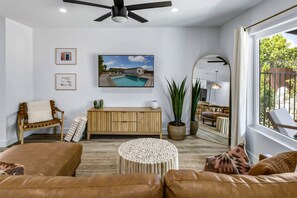 A modern living room with a pool view, a wooden console, a round white table, and a large mirror. - Chic Boho Vibes Meet Sunny Days and Starry Nights - Relaxation, and Adventure (Palm Springs)