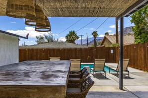 A patio area with a table, chairs, a pool, and a wooden fence. - Chic Boho Vibes Meet Sunny Days and Starry Nights - Relaxation, and Adventure (Palm Springs)