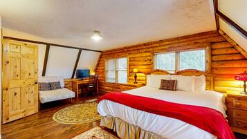 Un dormitorio de cabaña de madera con una cama grande, un escritorio con silla y una puerta de madera.