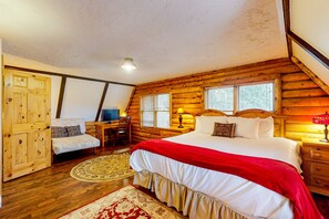 Un dormitorio de cabaña de madera con una cama grande, un escritorio con silla y una puerta de madera.