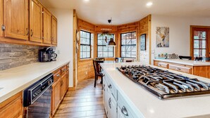 A modern kitchen with wooden cabinets, a large island with a stove, and a stone backsplash.