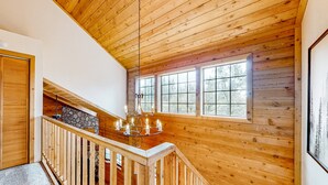 A wooden staircase with a stone wall and a chandelier.