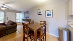 A dining area with a wooden table and chairs, a ceiling fan, and framed pictures on the wall. - Sun Valley condo with a patio, washer/dryer, & AC - pool, hot tub, grill access (Scottsdale)