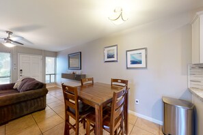 A dining area with a wooden table and chairs, a ceiling fan, and framed pictures on the wall. - Sun Valley condo with a patio, washer/dryer, & AC - pool, hot tub, grill access (Scottsdale)