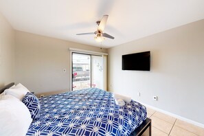 A hotel room with a bed, a ceiling fan, a TV mounted on the wall, and a view of the outside through a sliding door. - Sun Valley condo with a patio, washer/dryer, & AC - pool, hot tub, grill access (Scottsdale)