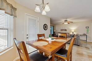 A dining area with a wooden table, chairs, a chandelier, and a ceiling fan. - Stylish & Spacious Condo with Pool, Spa & Gym | Minutes to Golf (Scottsdale)