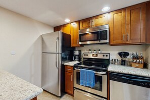 A modern kitchen with stainless steel appliances, wooden cabinets, and granite countertops. - Stylish & Spacious Condo with Pool, Spa & Gym | Minutes to Golf (Scottsdale)
