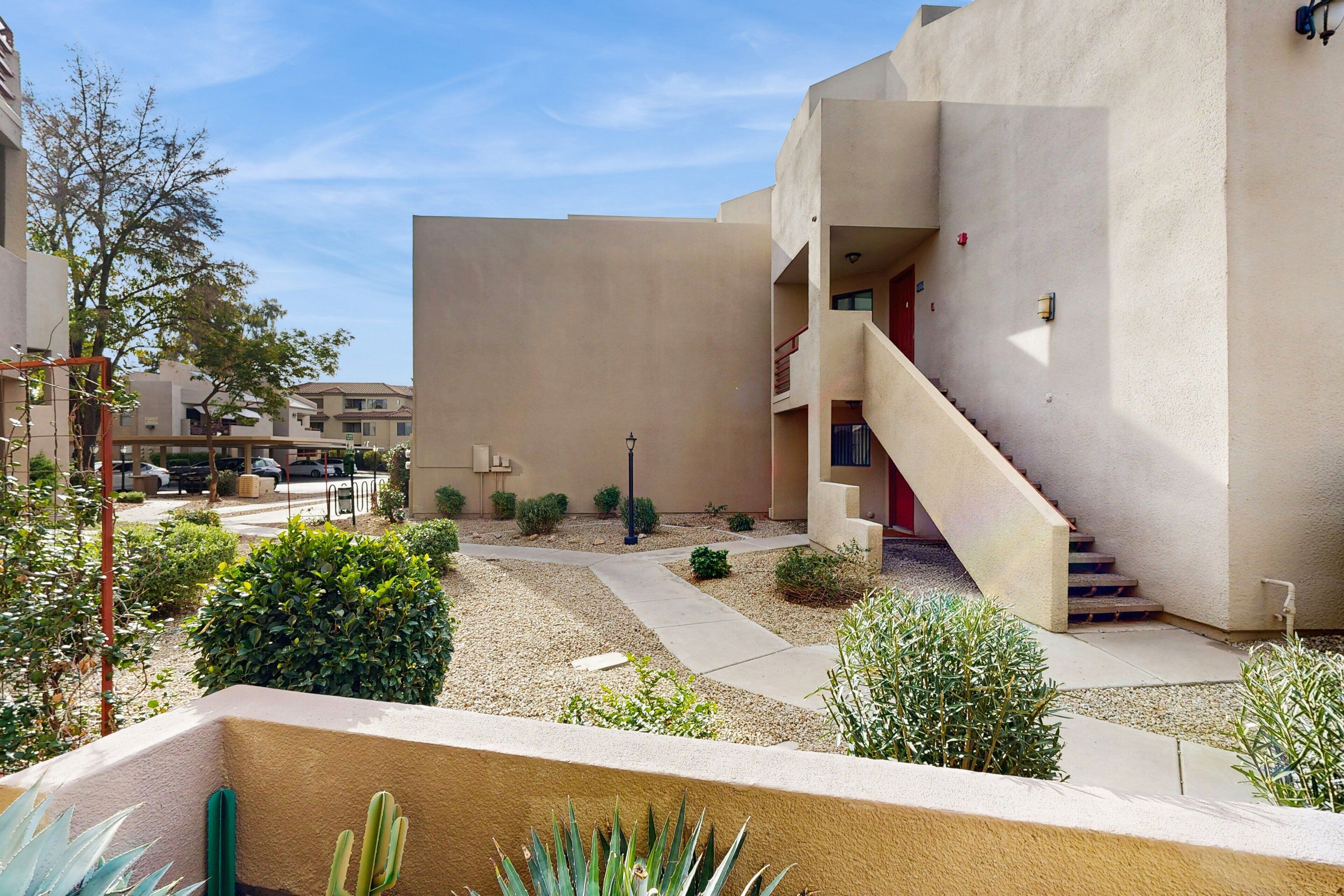 A residential building with a courtyard, a staircase, and a red door.