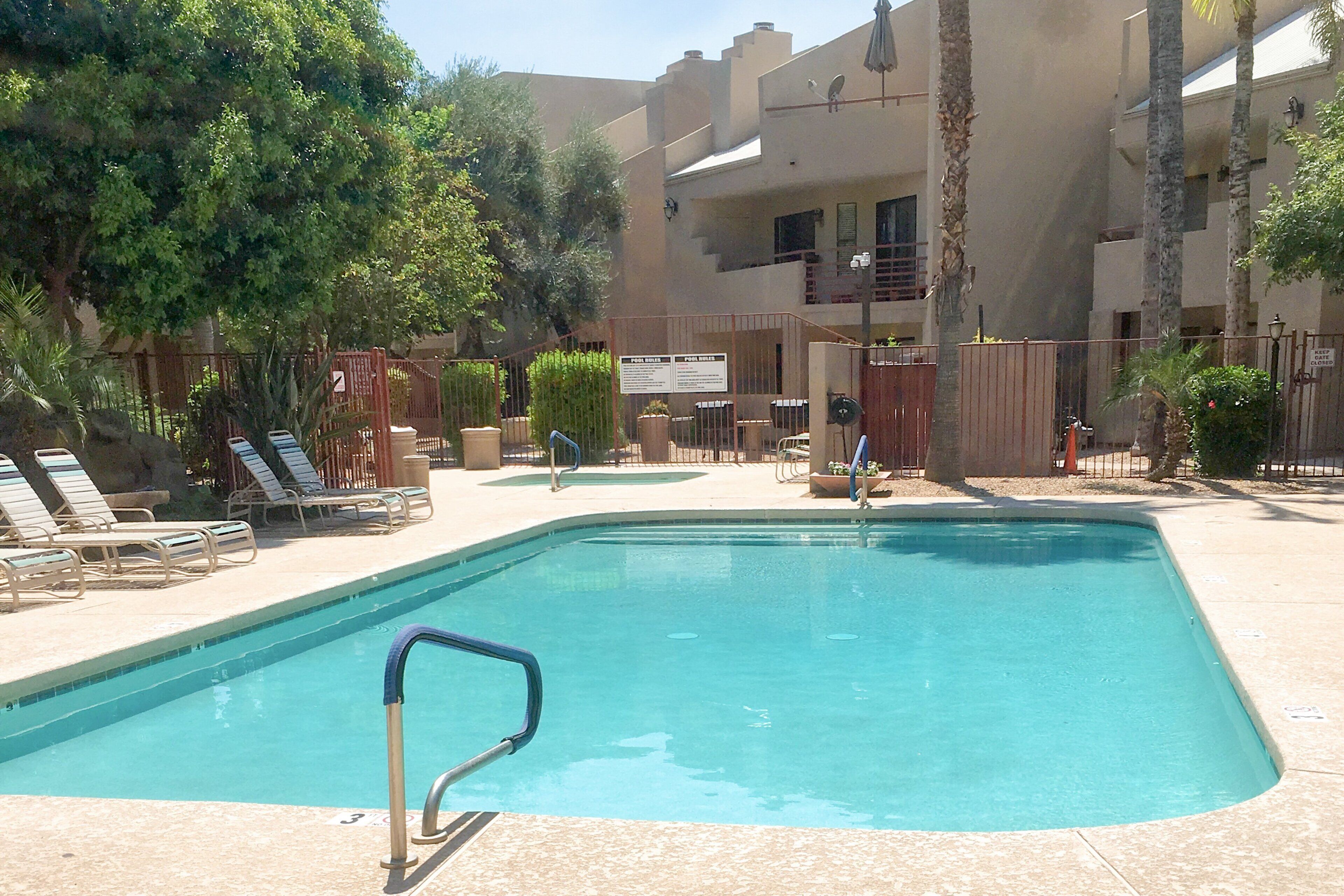 A swimming pool with lounge chairs and a fence.