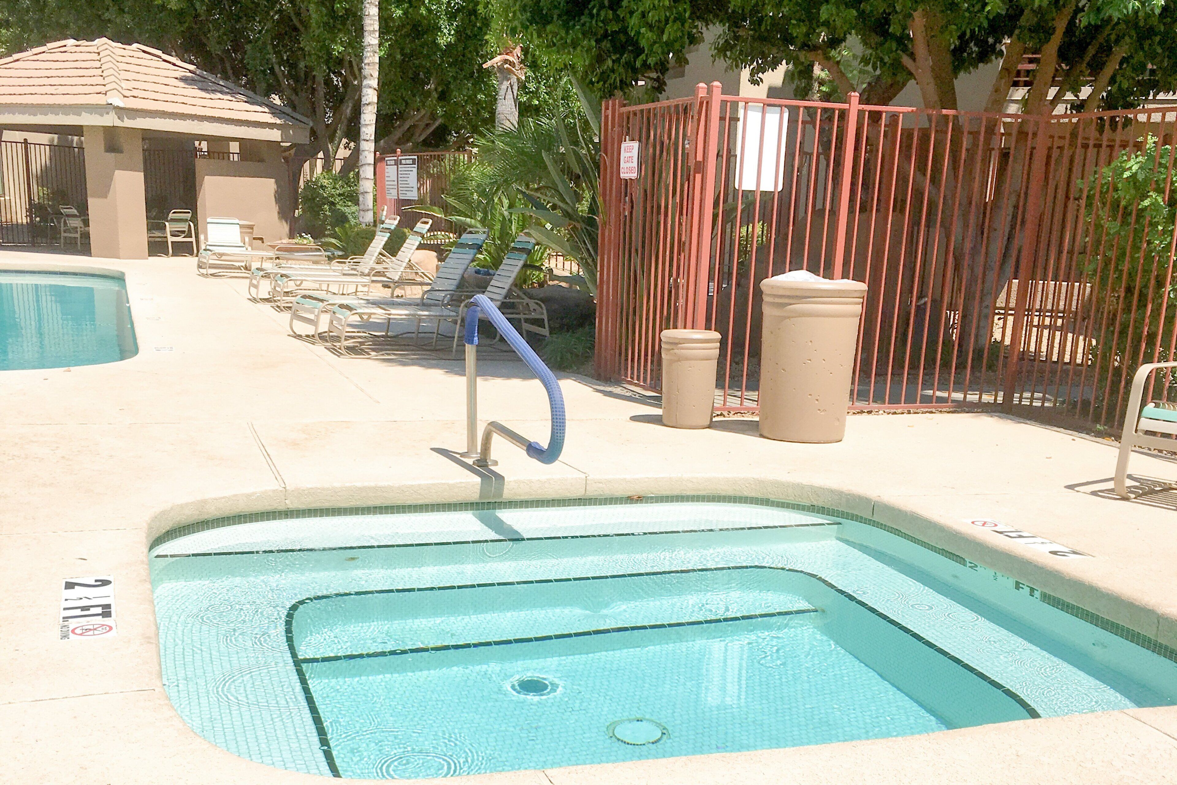 Una piscina con trampolino, lettini e un'area recintata con un cartello.