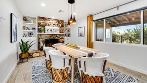 A modern kitchen with a stone backsplash, white cabinetry, and a large window with a view of greenery. - Lovely, updated home with enclosed yard, fast WiFi, W/D, & mountain view (Scottsdale)