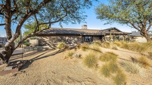 A rustic building with a sloped roof, surrounded by dry grass and trees. - Lovely, updated home with enclosed yard, fast WiFi, W/D, & mountain view (Scottsdale)