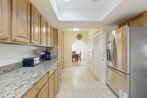 Eine Küche mit Granit Arbeitsplatten, Holzschränken, einem Edelstahlkühlschrank und einem Essbereich mit Tisch und Stühlen.