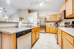 Una cocina moderna con armarios de madera, electrodomésticos de acero inoxidable y lavavajillas.