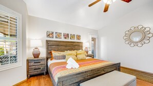 Quarto com cama de madeira, mesa de cabeceira, luminária e janela com persianas.