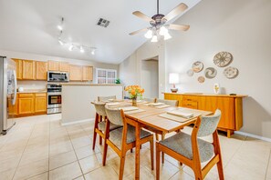 Una cocina moderna con armarios de madera, una mesa de comedor con sillas y un ventilador de techo.